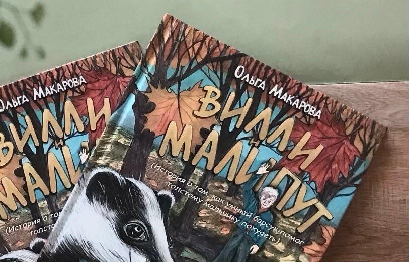 Два печатных экземпляра книги «Вилли и Малипут» на деревянном столе